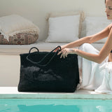 Woman sitting by a pool with a black beaded bag