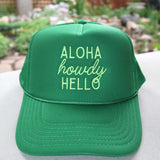 Green cap with 'Aloha howdy HELLO' text on a blurred natural background