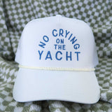 White cap with 'No Crying on the Yacht' text on a checkered fabric background
