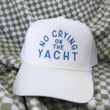 White cap with 'No Crying on the Yacht' text on a checkered fabric background