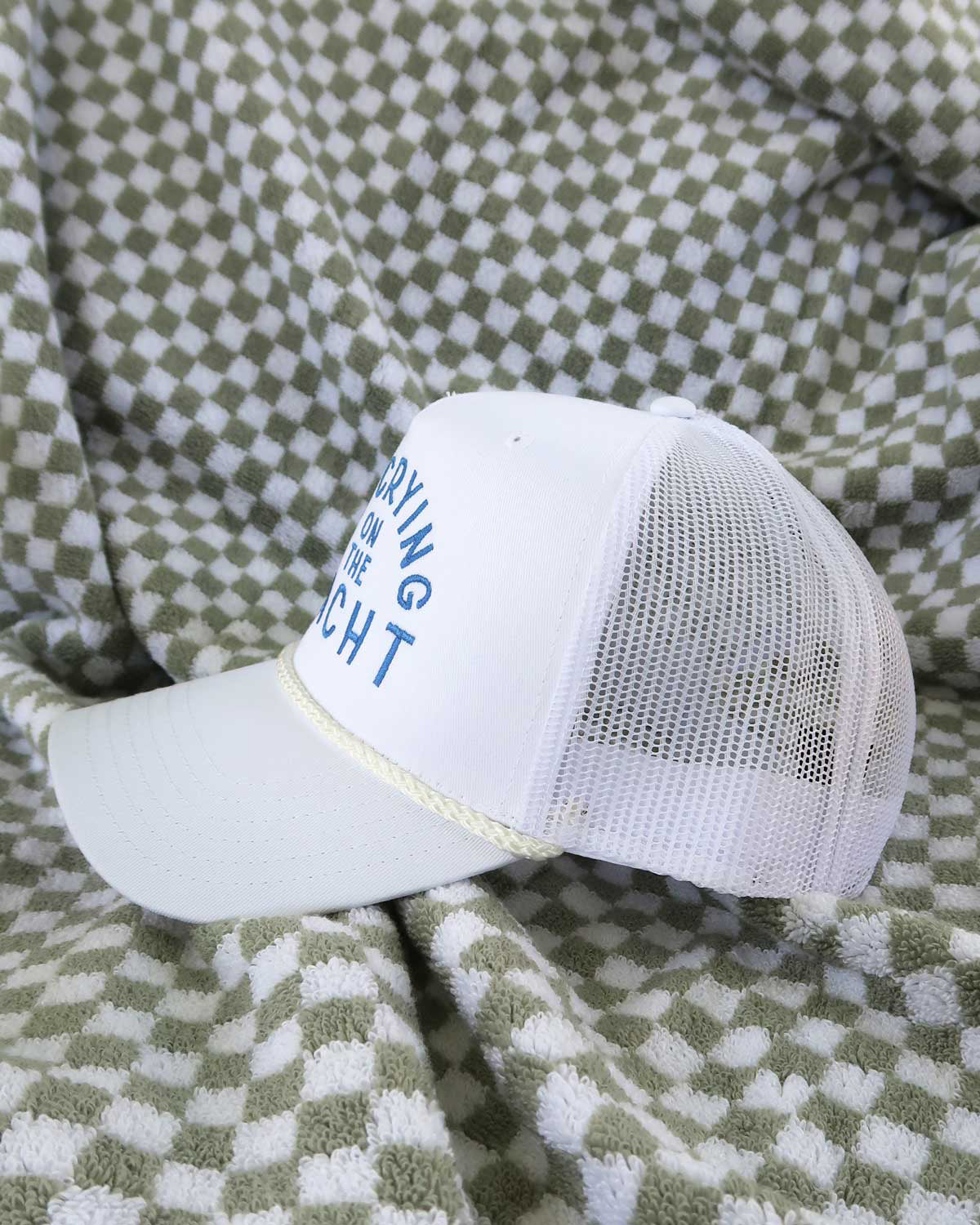 White cap with blue text on a green and white checkered blanket