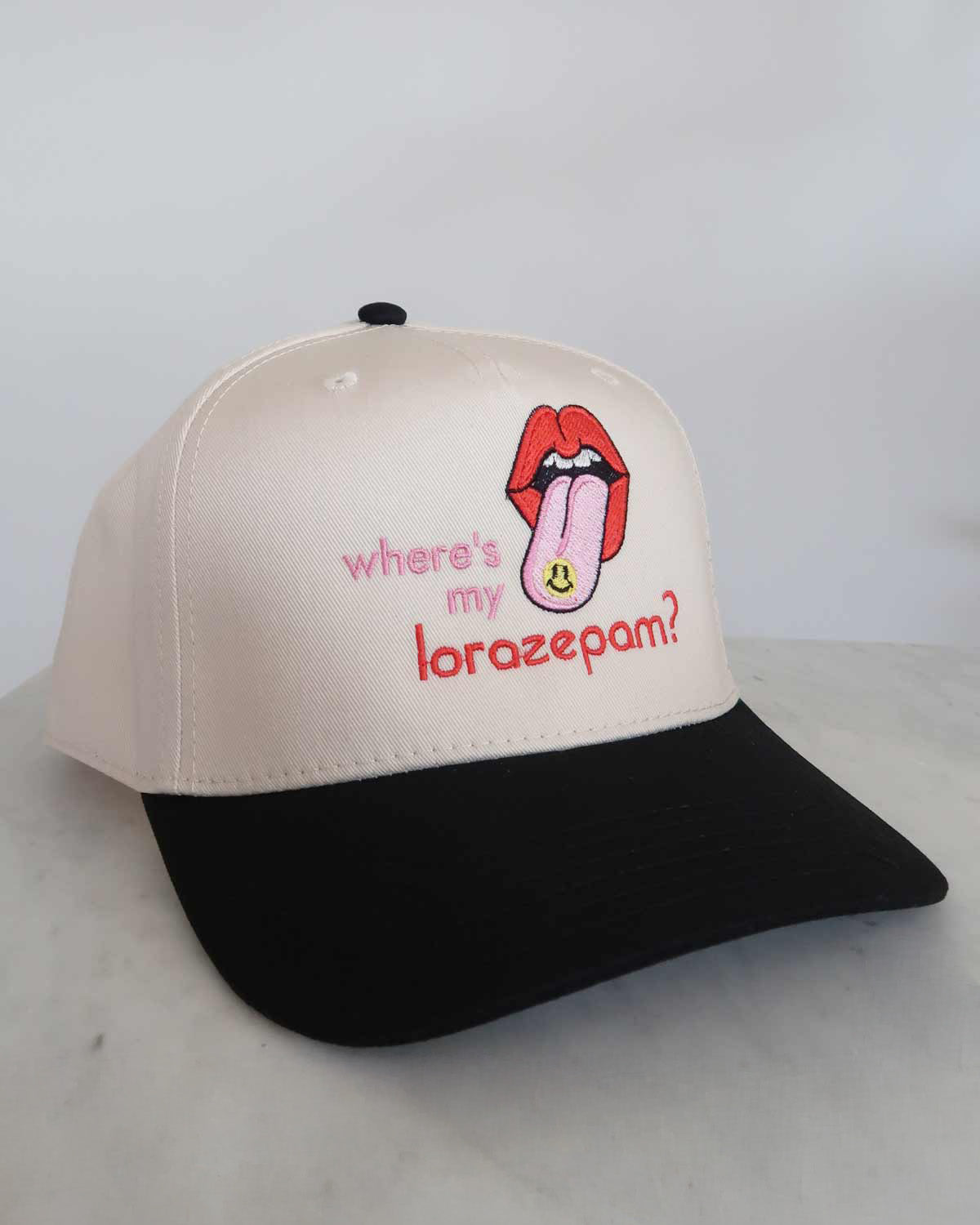 Beige and black cap with a graphic of a tongue and text on a white background