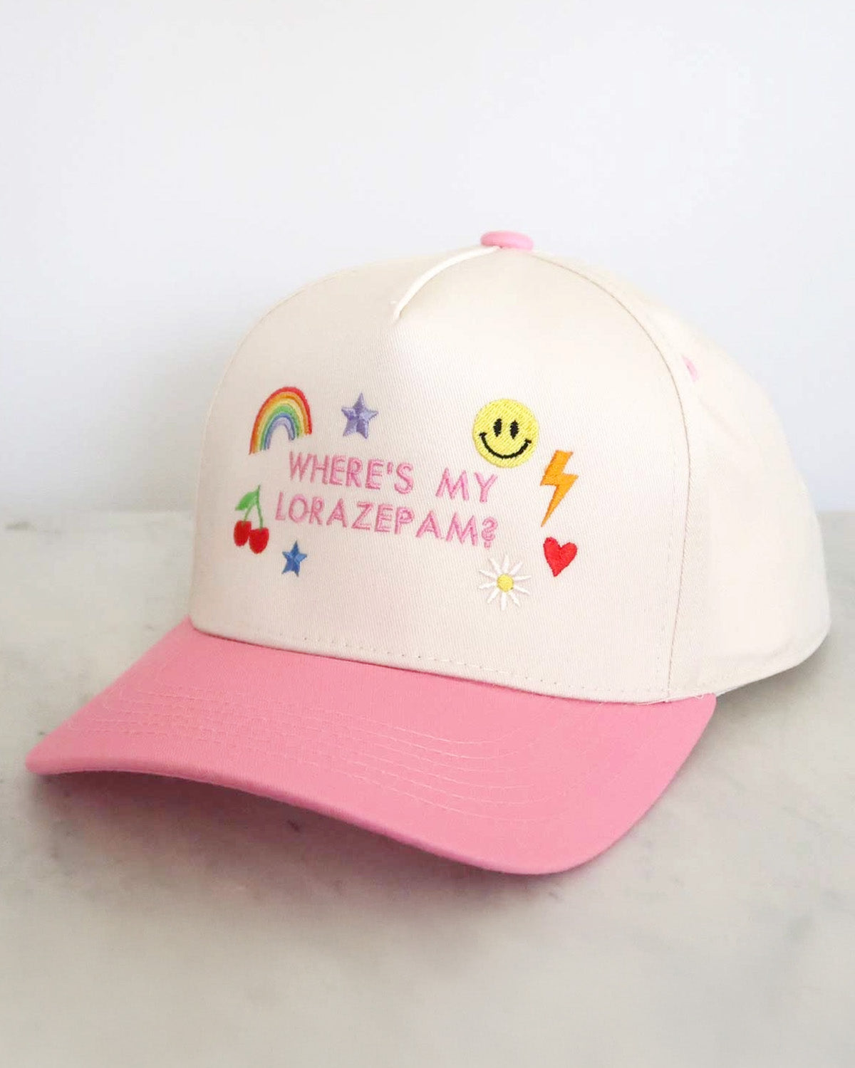 Pink and white cap with colorful text and graphics on a light gray background