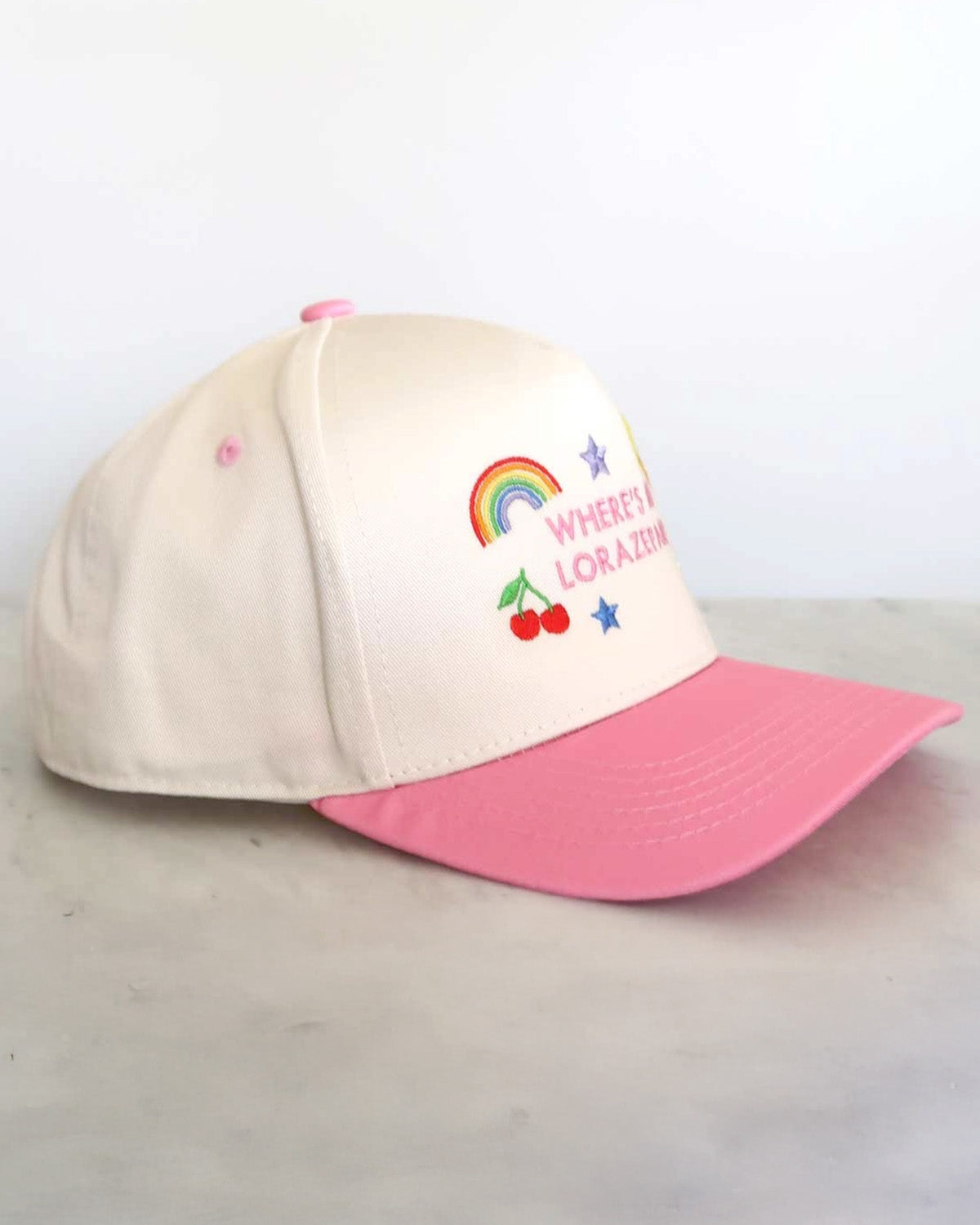Beige and pink cap with embroidered design on a light gray background