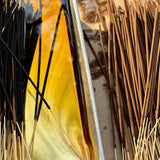 Incense sticks with a tray of melted wax or resin on a reflective surface