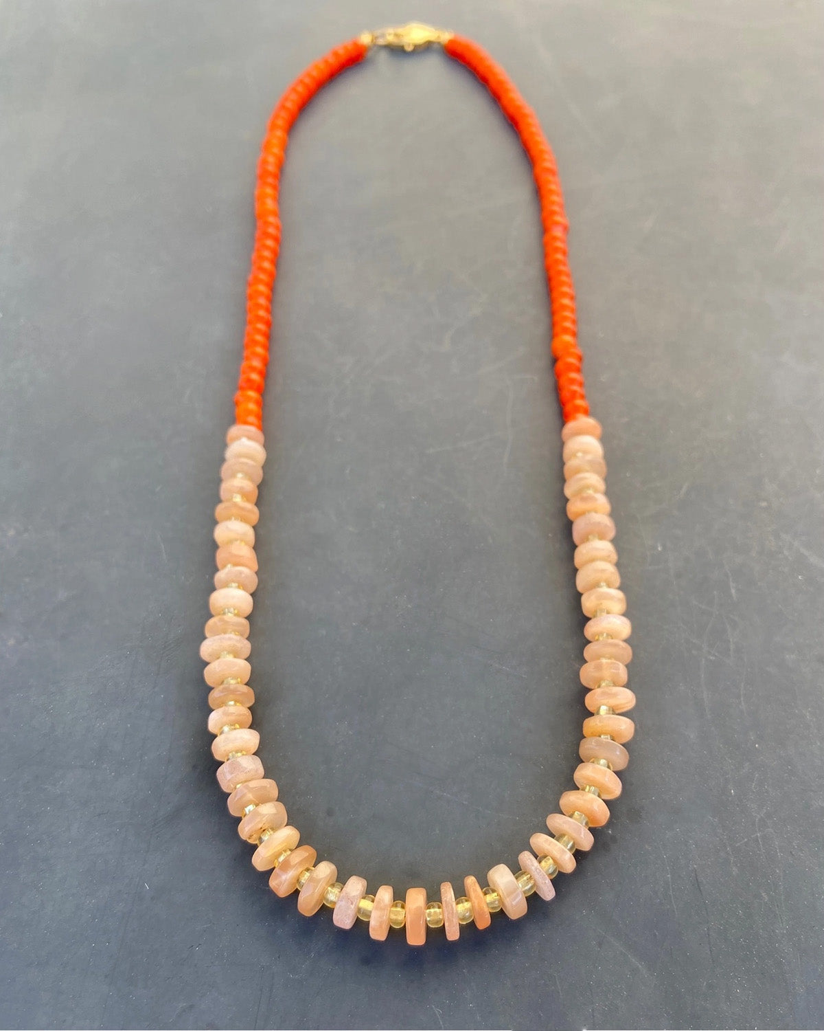 Necklace with orange and peach beads on a gray background