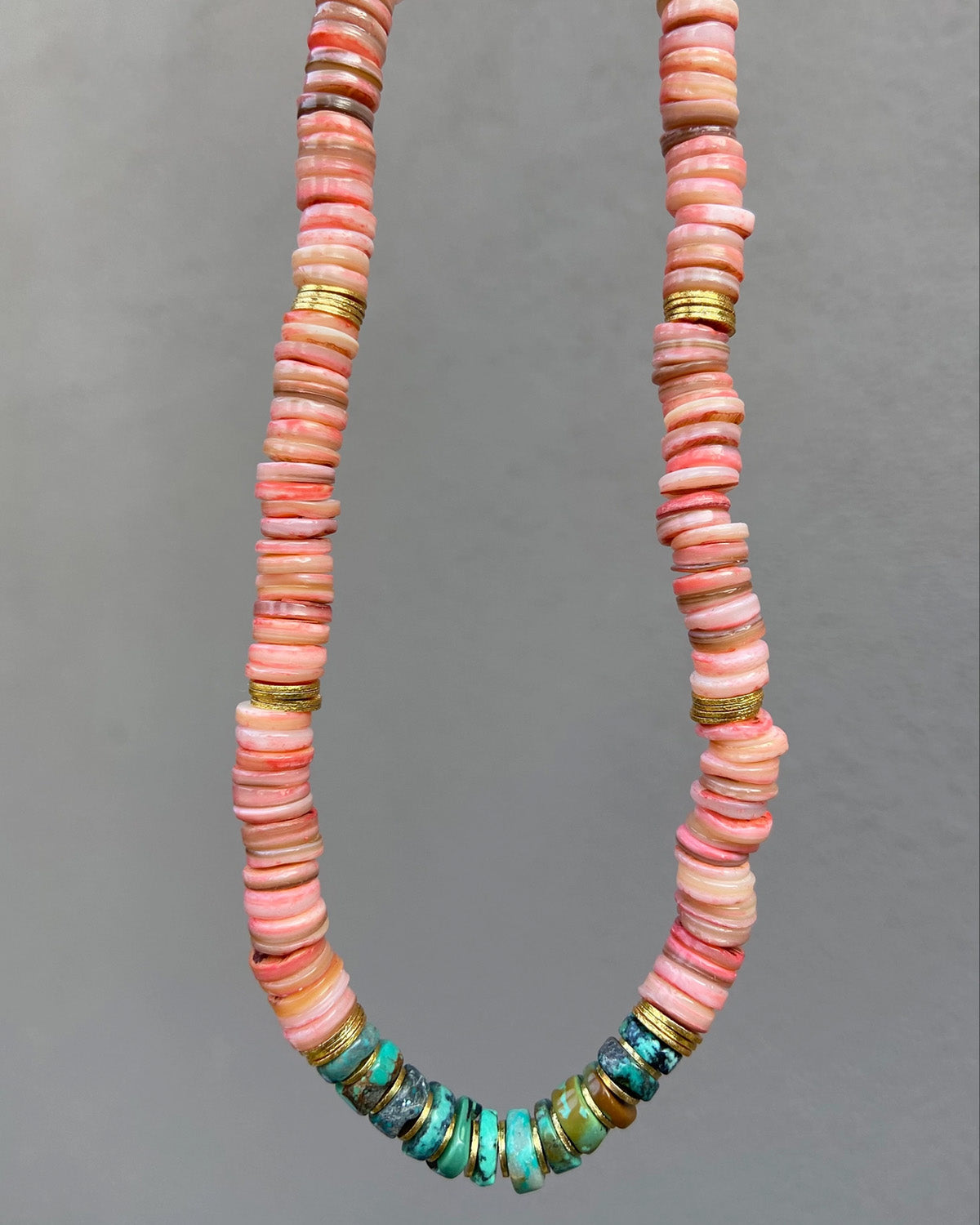 Necklace with pink and green beads on a gray background