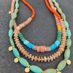 Three colorful beaded necklaces on a dark textured surface