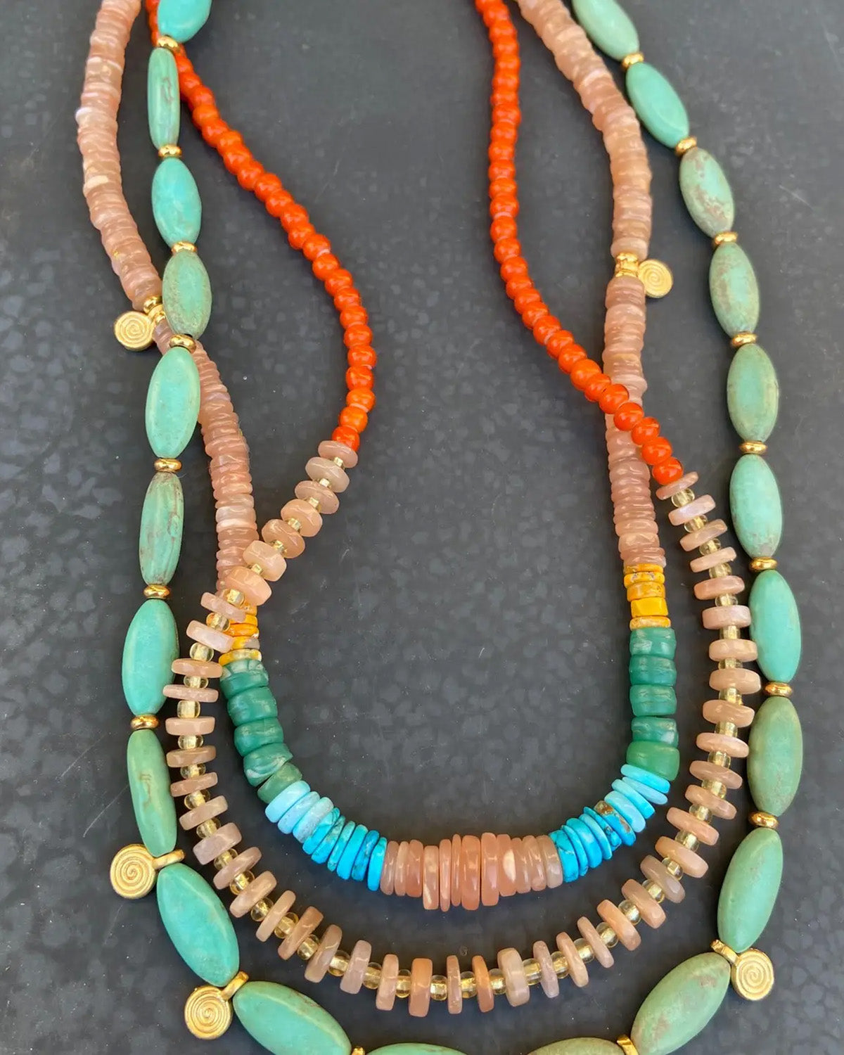 Colorful beaded necklaces on a dark textured surface