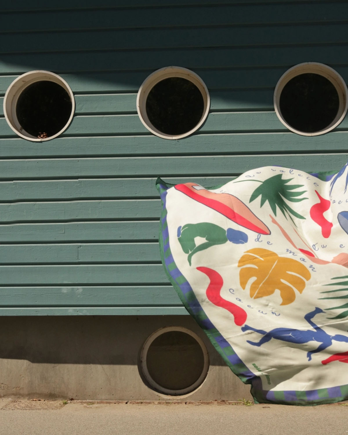 Colorful abstract design on a white surface against a green metal background with circular holes