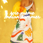 Person wearing a colorful dress with abstract designs on a yellow background, featuring text 'soie meme Indian Summer'
