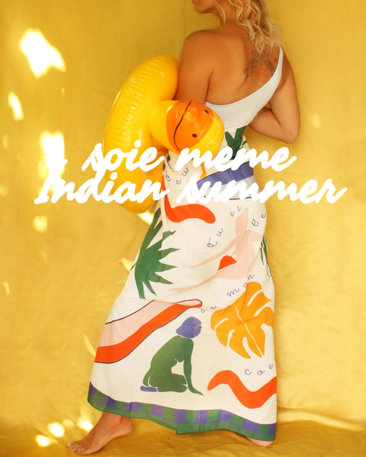 Person wearing a colorful dress with abstract designs on a yellow background, featuring text 'soie meme Indian Summer'