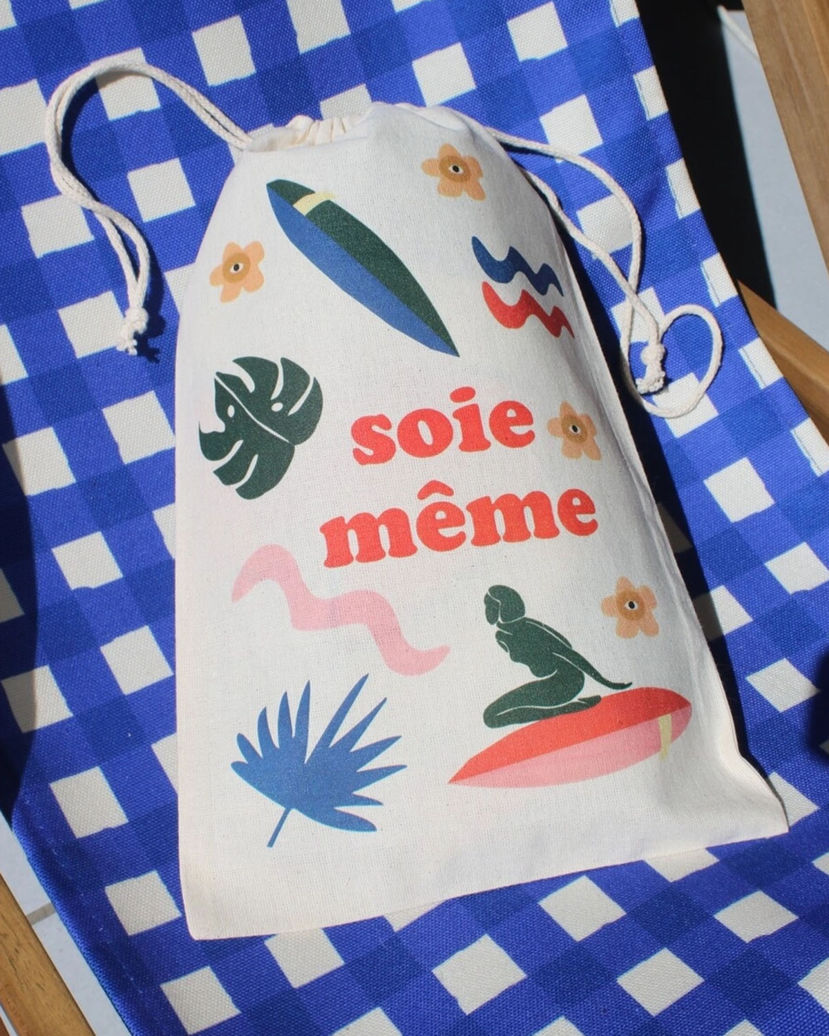 Drawstring bag with colorful graphics and text on a blue and white checkered background