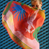 Person holding a colorful scarf with abstract designs against a blue lattice background