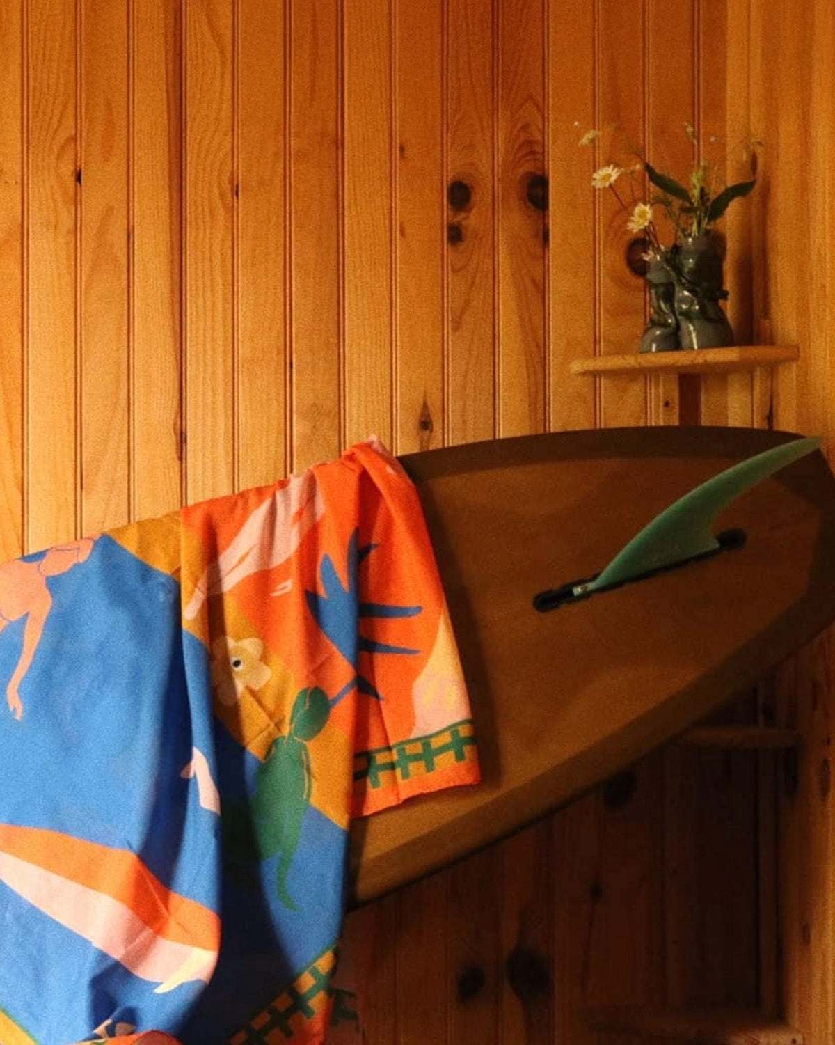 Colorful towel with animal patterns draped over a wooden surface against a wooden wall