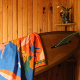 Colorful towel with animal patterns draped over a wooden surface against a wooden wall