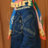 Person wearing a colorful jacket with 'surf collection' text and artistic design on an orange background