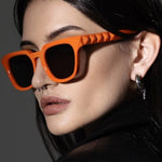 Person wearing orange sunglasses with a dark background
