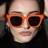 Person wearing bright orange sunglasses with hands on head