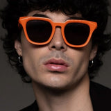 Person wearing orange sunglasses with a dark background