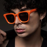 Person wearing orange sunglasses with a dark background