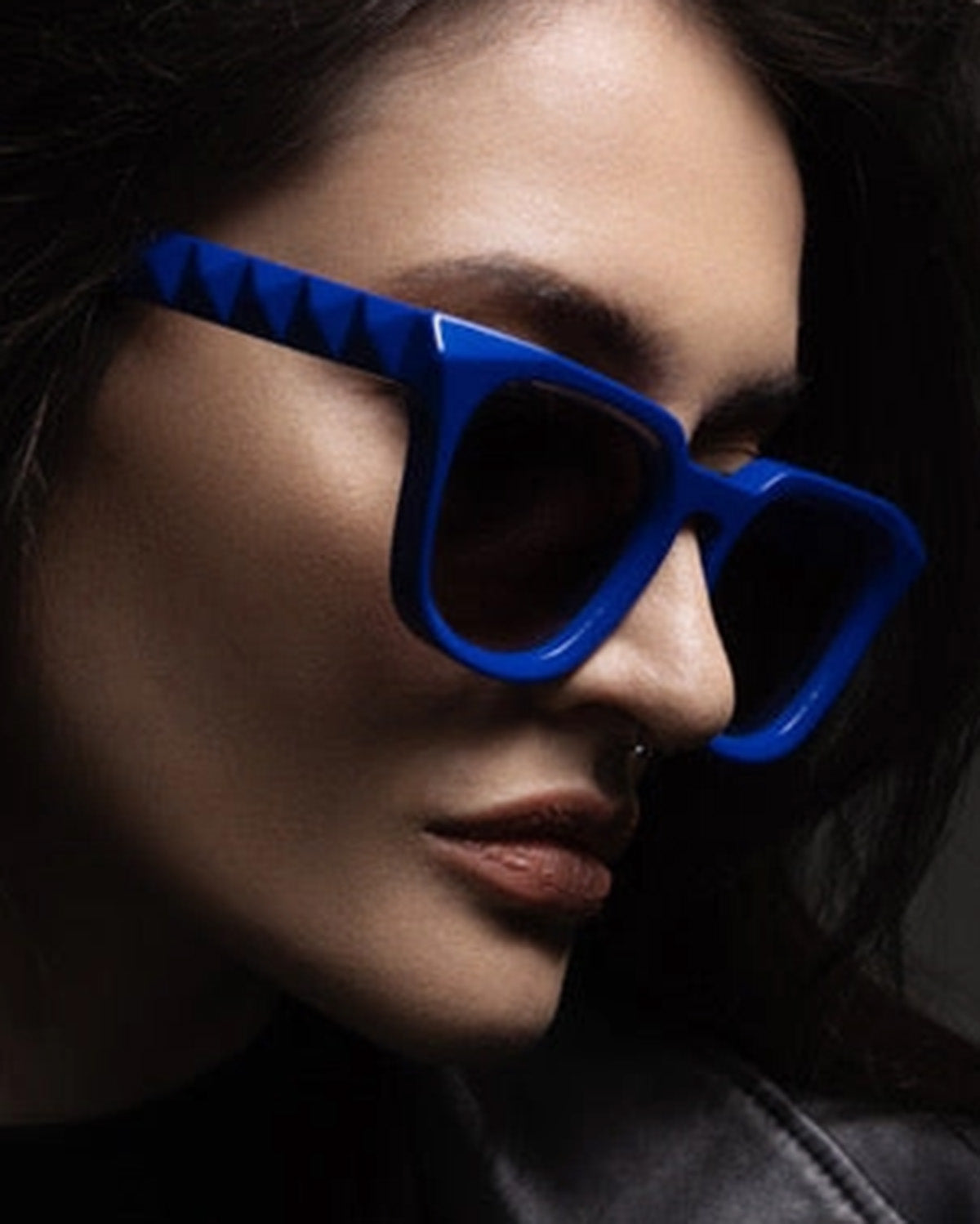 Person wearing blue sunglasses with a dark background