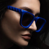 Person wearing blue sunglasses with a dark background