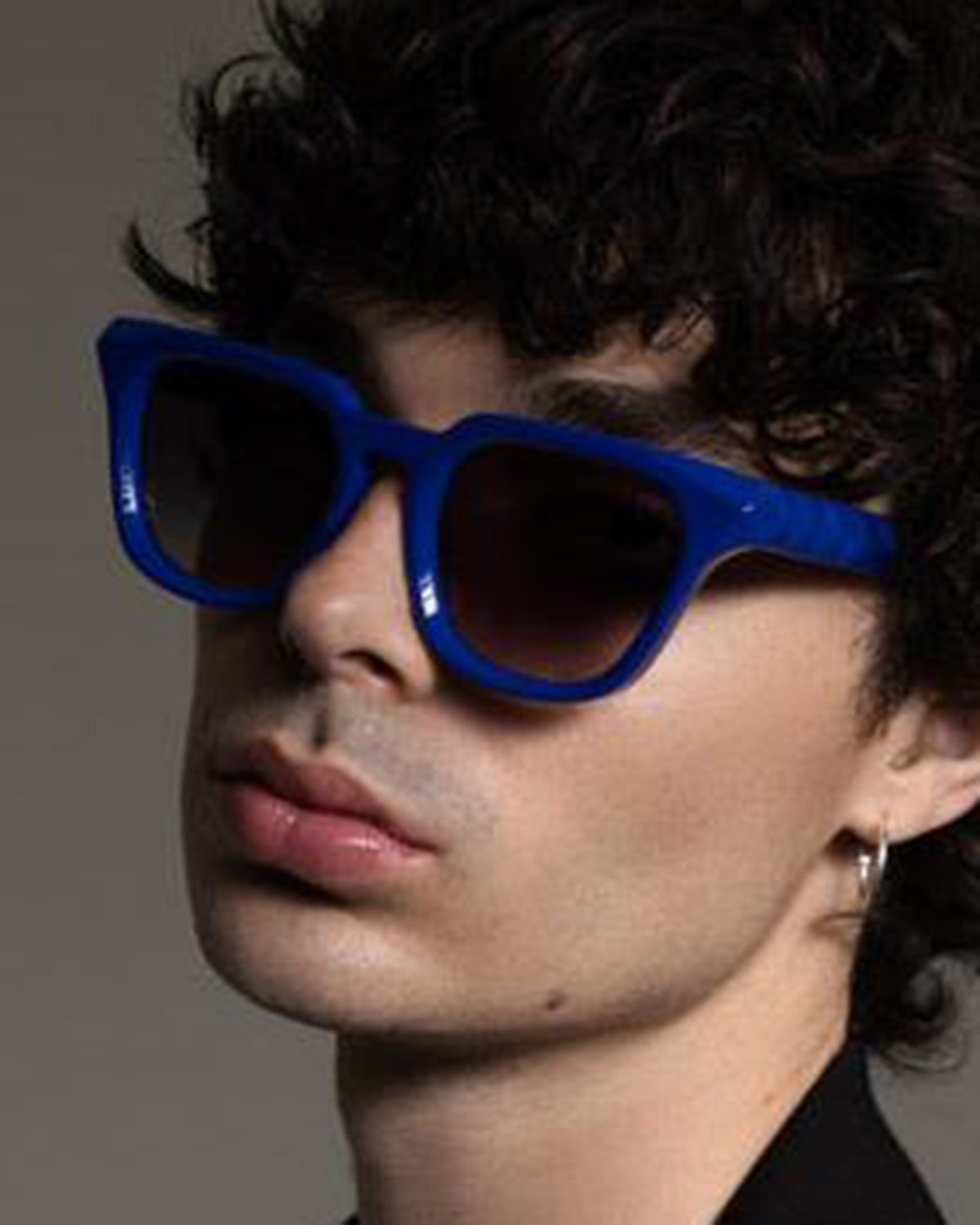 Person wearing blue sunglasses with a neutral background