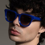 Person wearing blue sunglasses with a neutral background