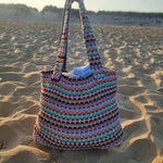 Colorful woven bag on a sandy beach