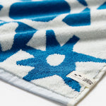 Close-up of a blue and white patterned towel with a brand tag