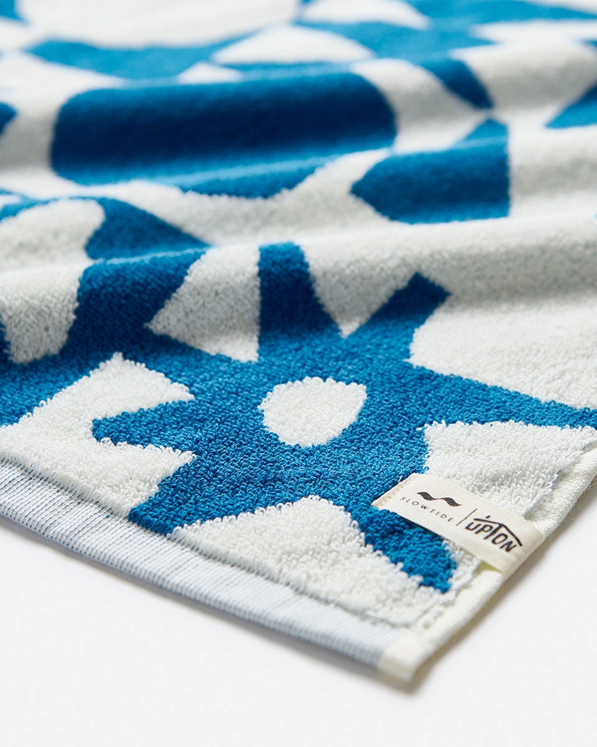 Close-up of a blue and white patterned towel with a brand tag