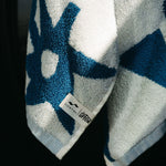 Blue and white towel with a brand label on a black background
