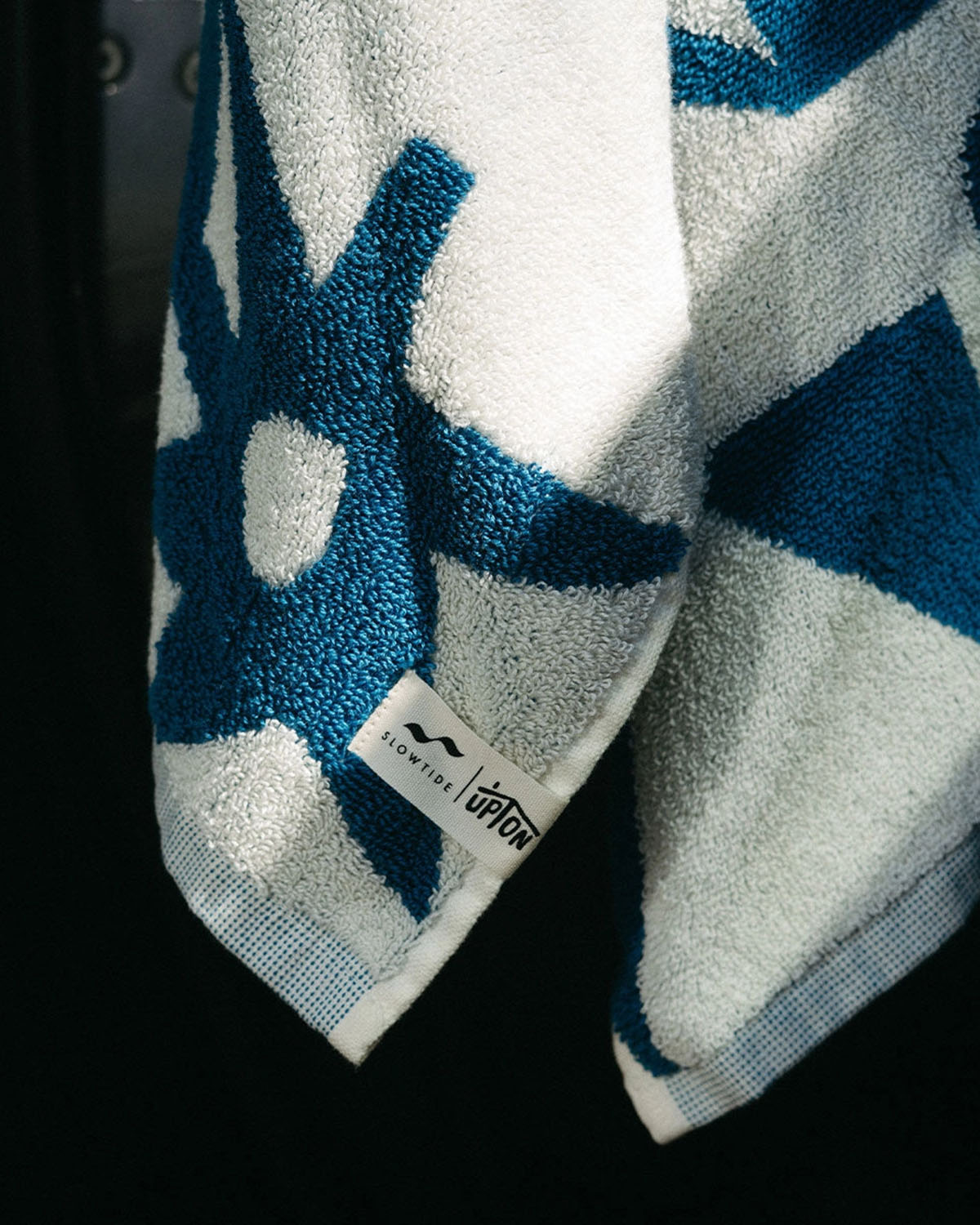 Blue and white towel with a brand label on a black background