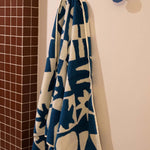 Blue and white patterned towel hanging on a hook against a tiled bathroom wall